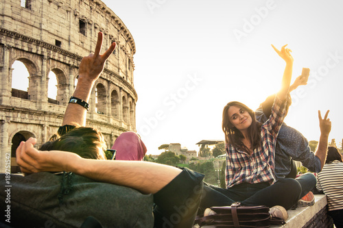 Photography Three young friends tourists sitting lying in front of colosseum in rome taking selfie pictures with smartphone camera
