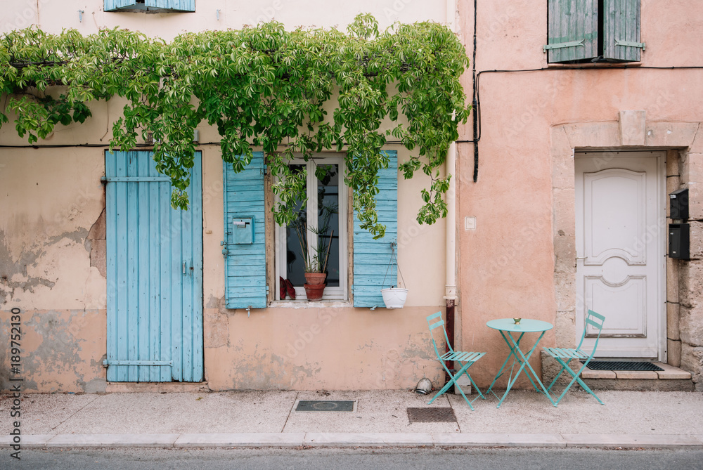 Naklejka premium Colourful house wall facade, orange damages cracked walls, blue door and shutters, Provence village, south France