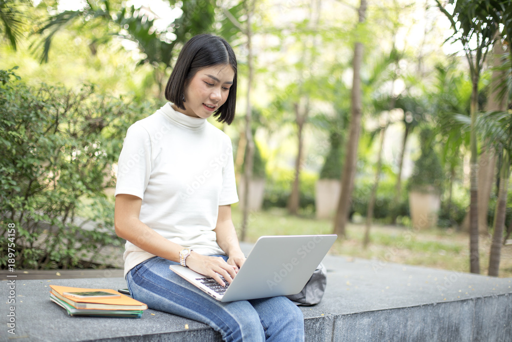 Asian Woman using laptop with attractive smiling at garden. People lifestyle concept. Asian Woman using laptop with attractive smiling at garden. People lifestyle concept.