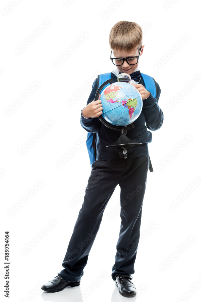 schoolboy examines through magnifier glass globe, portrait is isolated in full length on a white background schoolboy examines through magnifier glass globe, portrait is isolated in full length on a white background