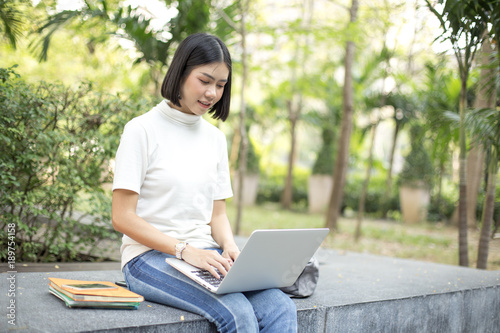 Asian Woman using laptop with attractive smiling at garden. People lifestyle concept. © Bavorndej