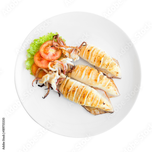Grilled squid with a leaf of lettuce and tomato on a white plate