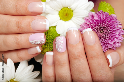 Fotografia Hands with french manicured nails and a bouquet of flowers
