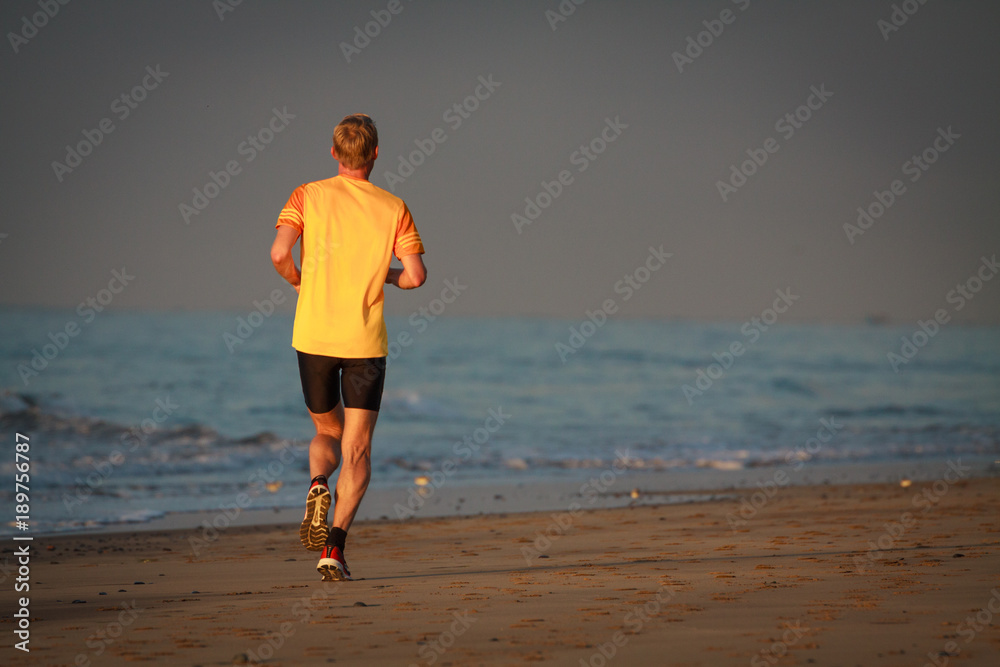 Man is running by the beach at sunrise.