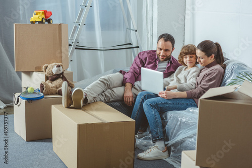 family with one child using laptop while moving in new home © LIGHTFIELD STUDIOS