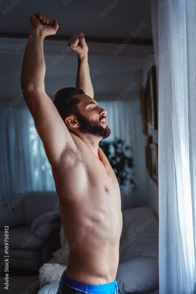 Obraz na plátně Shirtless man stretching by the window