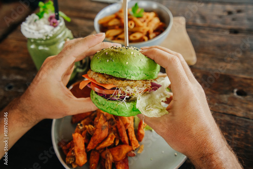 Obraz na plátně vegetarian green burger in the hands of a man