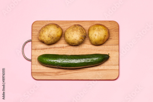 Healthy Eating. Three Fresh Potatoes Near Cucumber On A Wooden Chopping Board photo