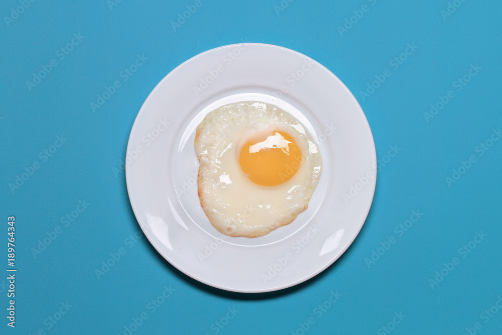 Fried Eggs In A White Plate On A Blue Background Fried Eggs In A White Plate On A Blue Background