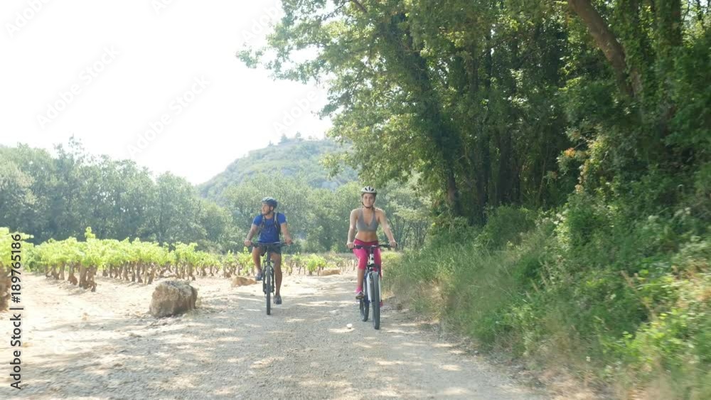 happy young couple riding bicycle in countryside during summer