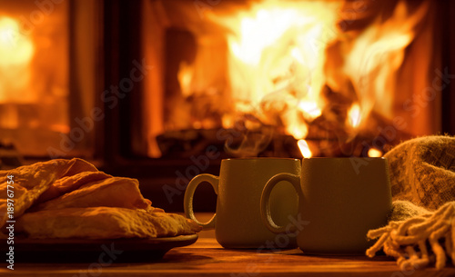 Steam from a cups with a hot cocoa on the fireplace background. 