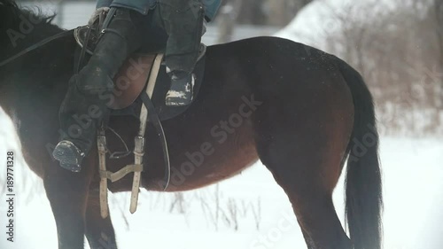 Cowgirl young woman gets off from her horse at winter snowfall photo