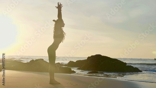 Silhouette yoga practice at sunset. Yong woman doing yoga exercise on the beach