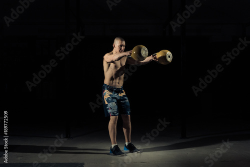 A strong man picks up kettlebell in gym. Sportlife