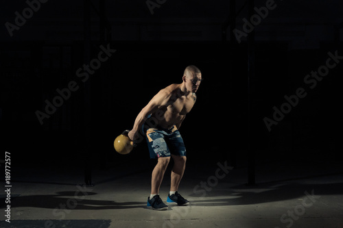 A strong man picks up kettlebell in gym. Sportlife