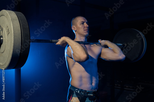 An athlete lifts a barbell on his chest in the gym