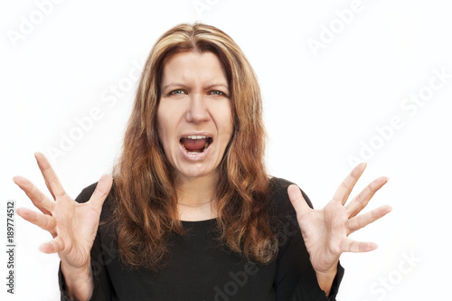 Beautiful woman with an angry face on white background. She shouts and emotionally shakes hands