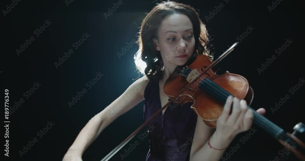 a talented girl violinist performs at her first solo concert, stage light, dark background a talented girl violinist performs at her first solo concert, stage light, dark background