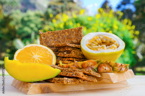 Granola bars with cereals over a wooden table and orange and passion fruit on blurred nature background photo