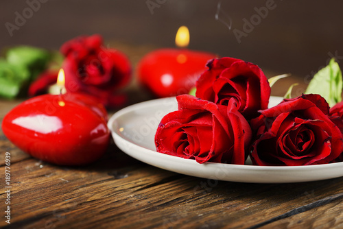 Red candles and roses on the wooden table