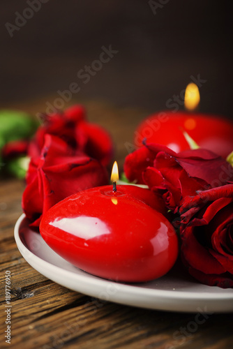 Red candles and roses on the wooden table