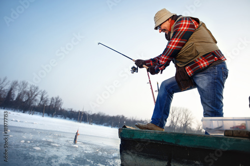 Fisherman draws hooked fish from frozen water