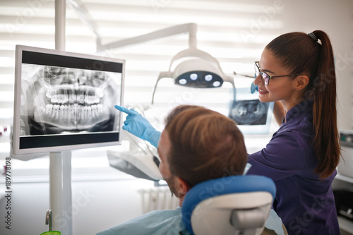 Dentist showing x-ray footage of teeth to patient photo