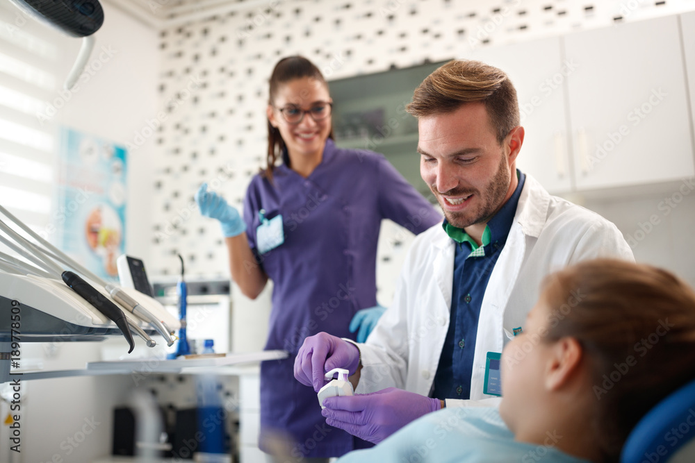 Obraz premium Dentist shows to girl how to brush her teeth