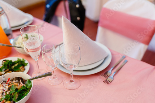 Napkin on a plate on the background of the snacks. Decorated the table. Banquet table decorated with flowers, napkins, glasses, candles and pink ribbons