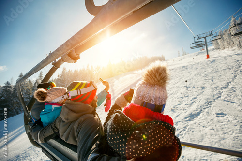 friends skiers and snowboarders on ski lift in the mountain at winter vacations