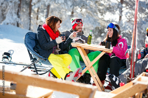 Happy friends spending time together and drink after skiing in cafe at ski resort