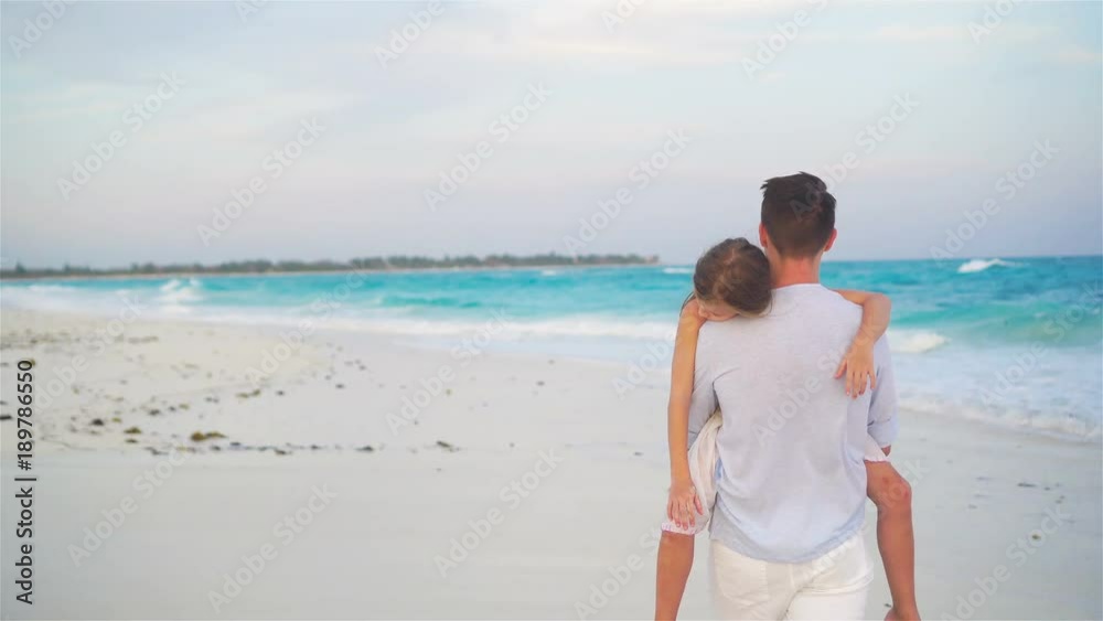 Adorable girl and young father at tropical beach. Family in the evening on the beach