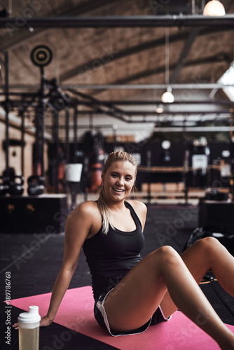 Fototapeta Naklejka Na Ścianę i Meble -  Smiling young woman taking a break from her gym workout