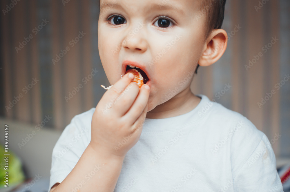 the child at home, at home eating Mandarin wedges, very happy the child at home, at home eating Mandarin wedges, very happy