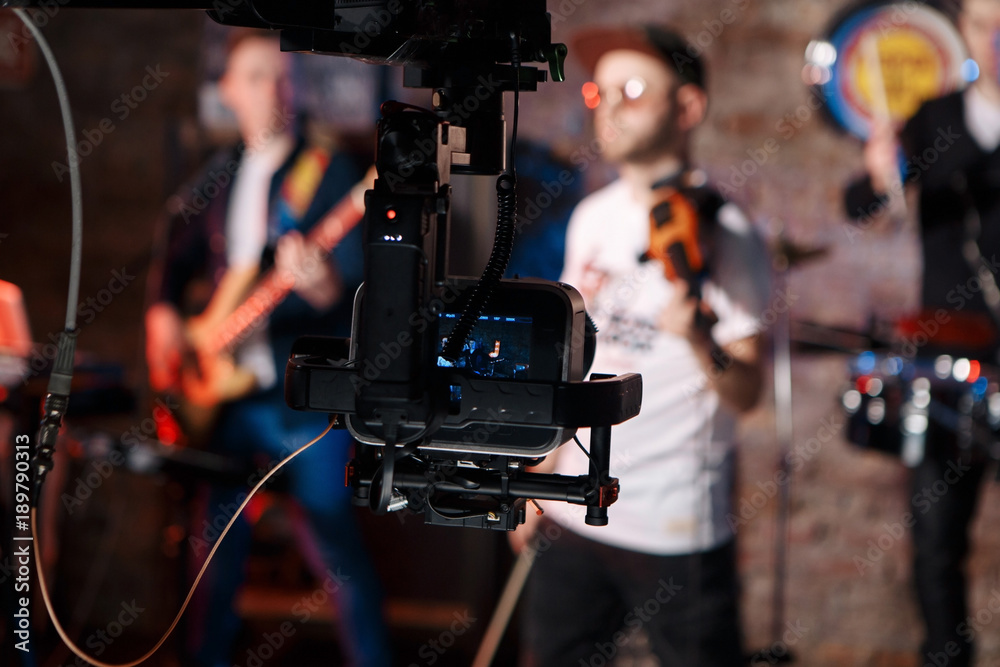 Silhouette of Television Camera hanging on crane working on stage and blurry concert background