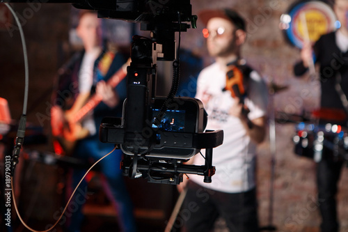 Silhouette of Television Camera hanging on crane working on stage and blurry concert background
