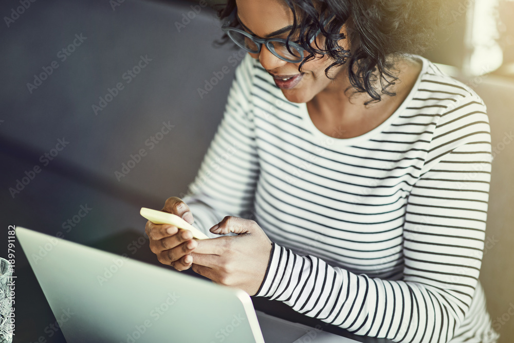 Young African woman using a laptop and reading text messages