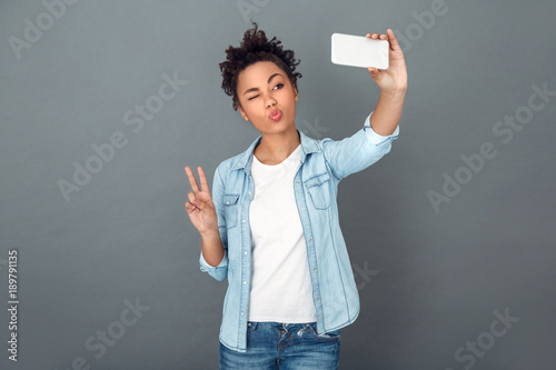 Cuadro en lienzo Young african woman isolated on grey wall studio casual daily lifestyle selfie p