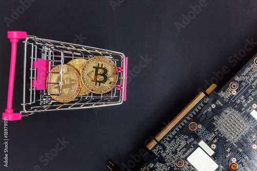 Stack of coins bitcoin in mini shopping cart toy on the video card, concept of mining. Electronic virtual money for web banking and international network payment. Symbol of crypto currency photo