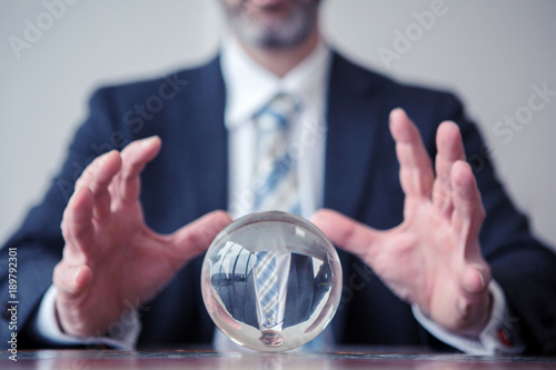 businessman looking at glass ball on table