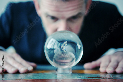 businessman looking at glass ball on table photo