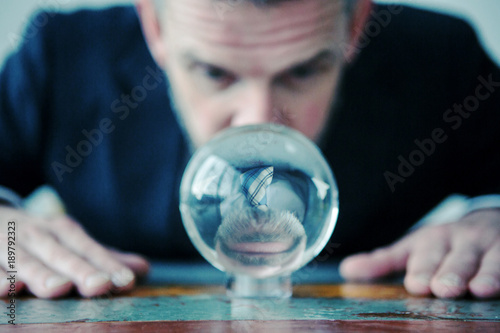 businessman looking at glass ball on table