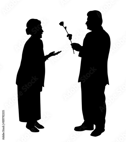 An elderly man gives a rose to an elderly woman