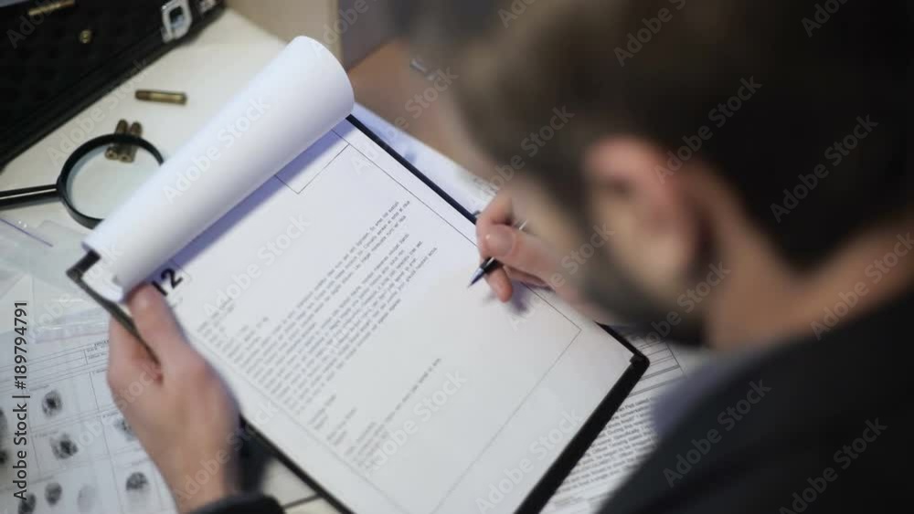 Detective reading and checking police report, solved murder case, back view