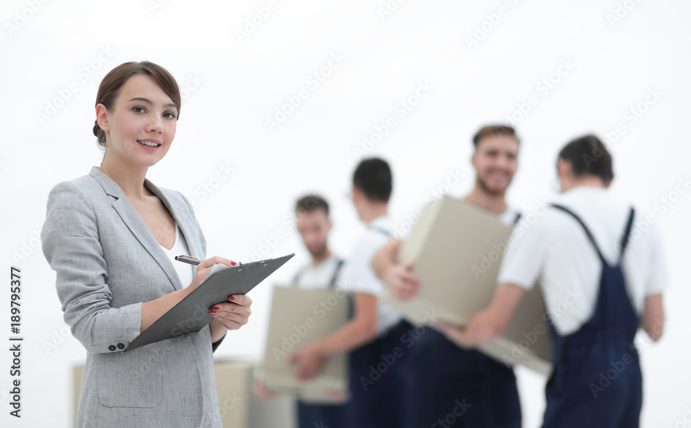 Woman manager holding clipboard on blurred background with mover Woman manager holding clipboard on blurred background with mover