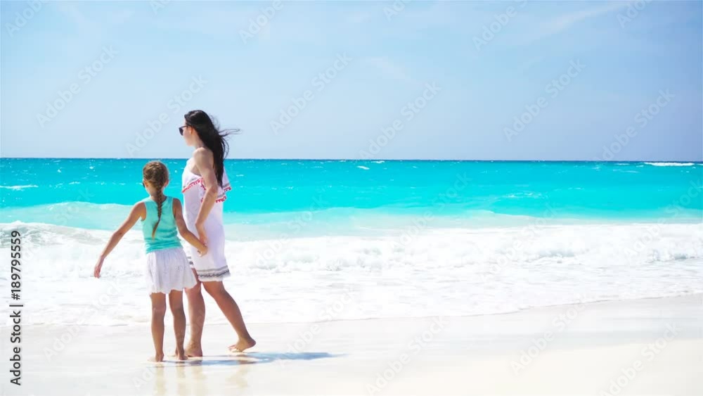 Little adorable girl and young mother at tropical beach. Family on caribbean vacation enjoy the sea view. Little adorable girl and young mother at tropical beach. Family on caribbean vacation enjoy the sea view.