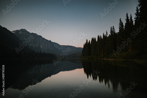 mountain lake reflects in the sunset with trees