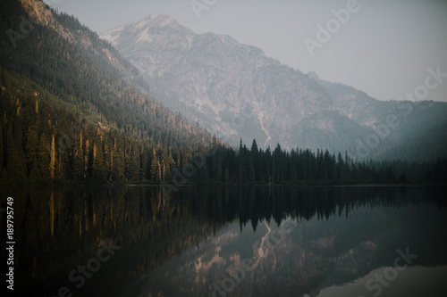 mountain lake reflects in sunrise with haze form fire