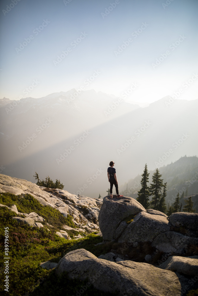 man looks out and takes pictures of valley below with hazy shadows