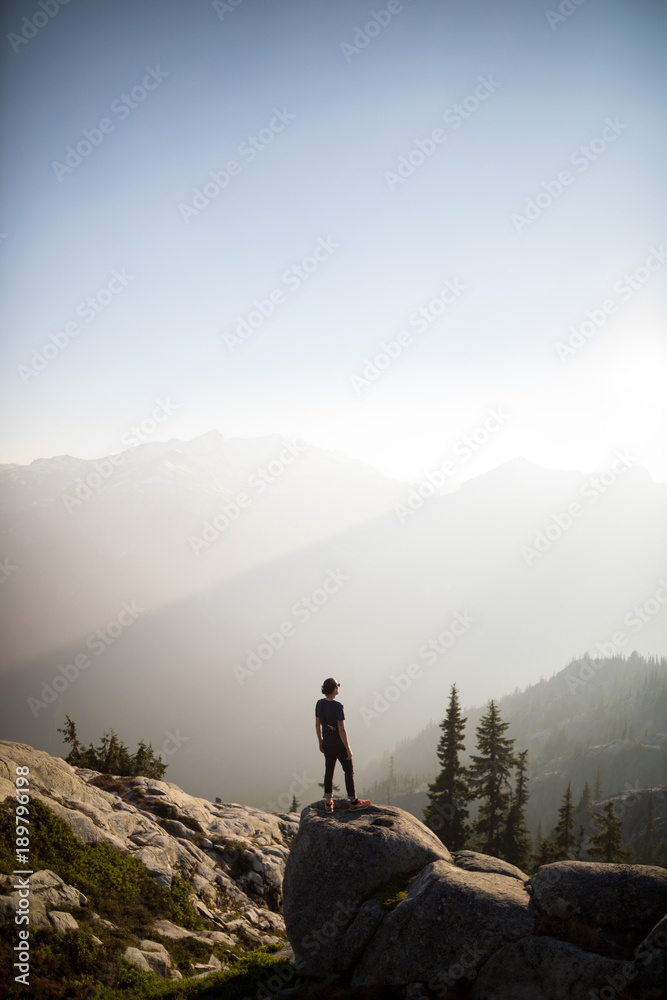 man looks out and takes pictures of valley below with hazy shadows